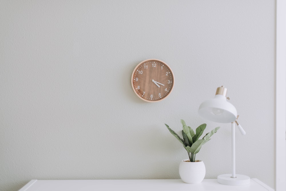 A wall with a counter, flower, lamp and a clock hanging on the wall